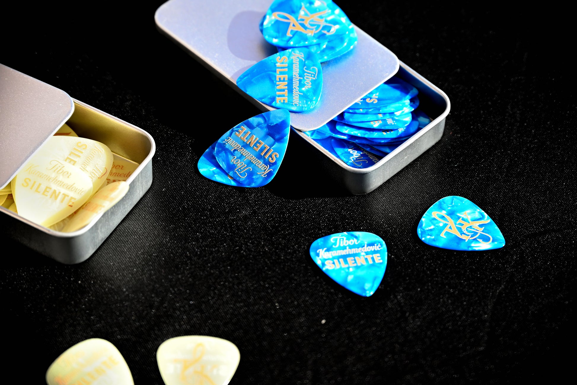 Blue and white guitar picks in a metal case on a black background