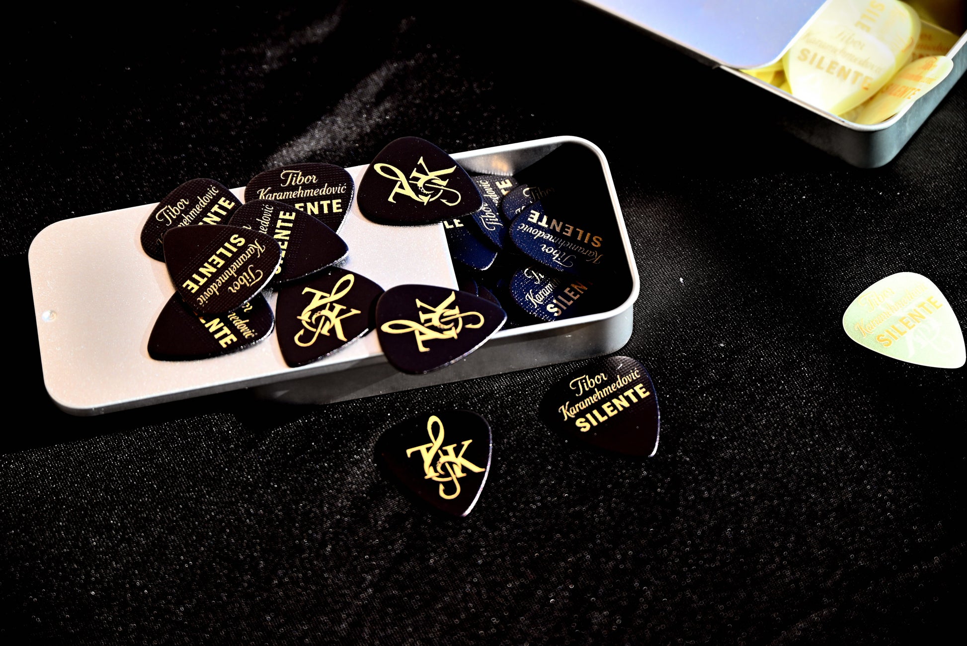 Guitar picks with gold text in a white case on a dark surface