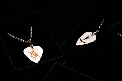 Guitar pick-shaped pendant and leaf-shaped earring on a black background