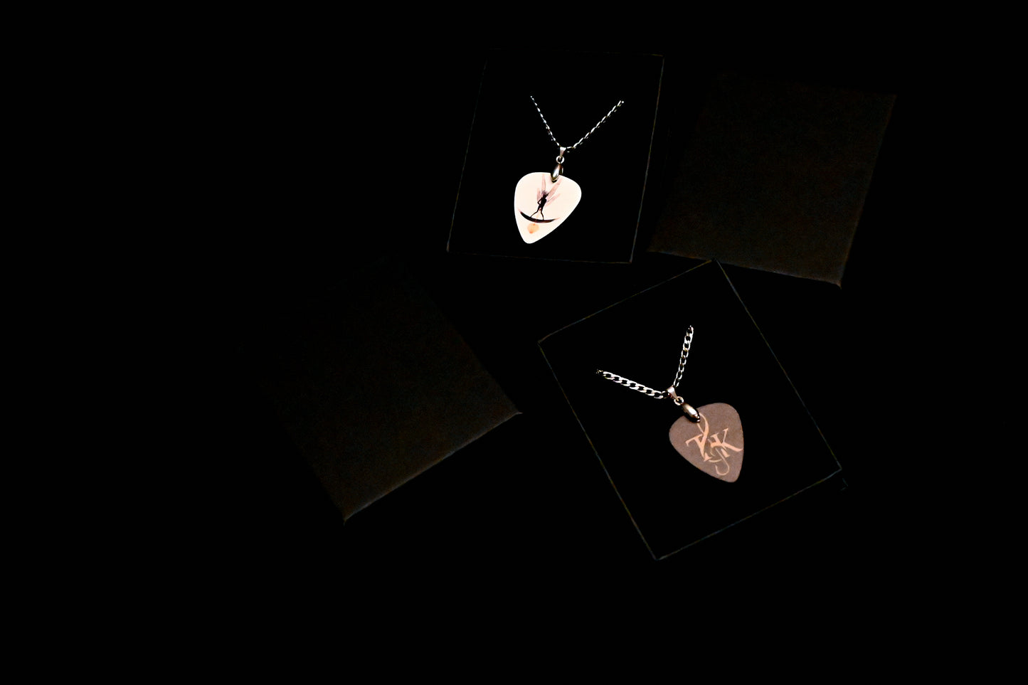 Two heart-shaped pendants on black cards with a dark background