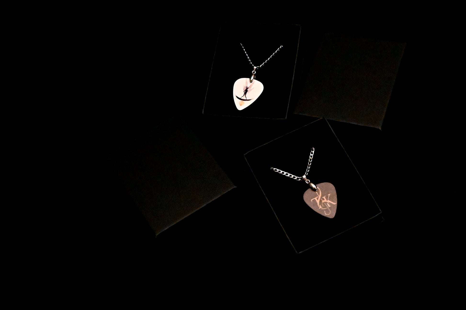 Two heart-shaped pendants on black cards with a dark background