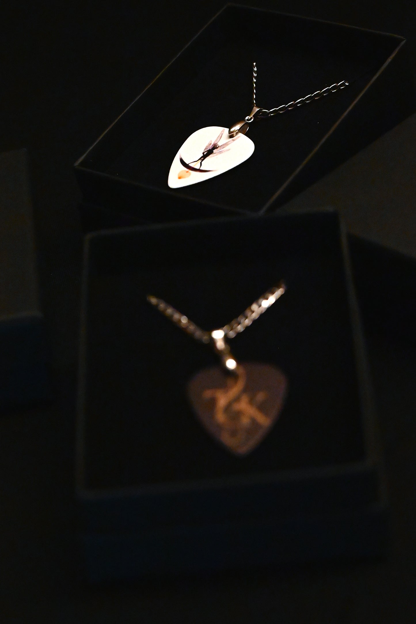 Two necklaces with unique pendants on a dark background