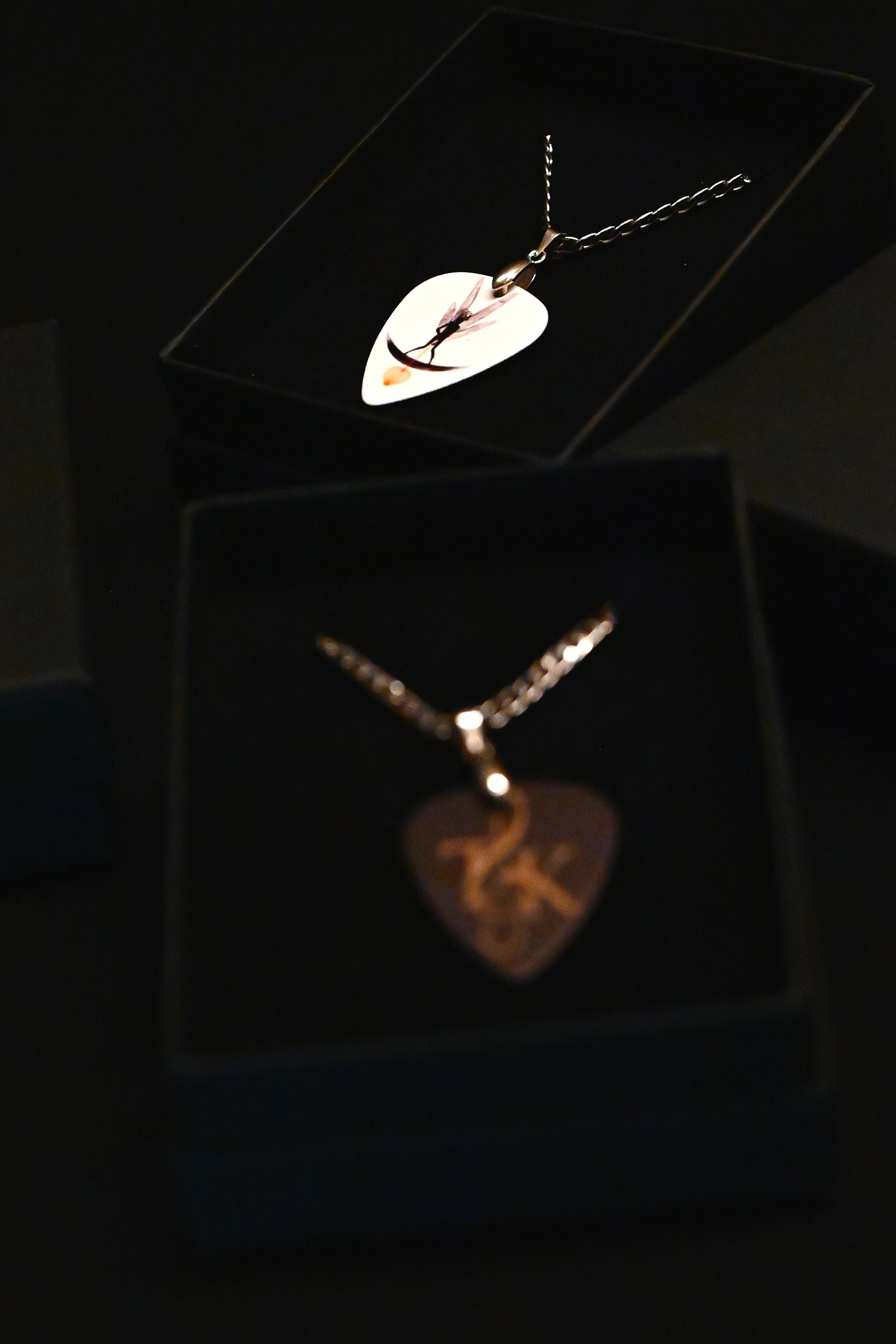 Two necklaces with unique pendants on a dark background